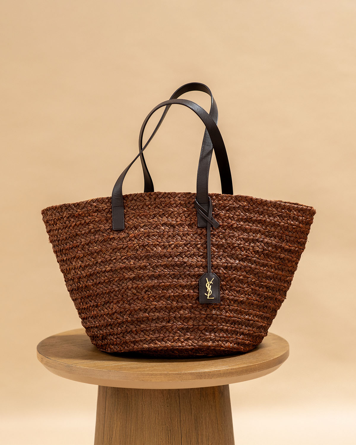 YSL Brown Woven Raffia Panier Tote on a wooden stool