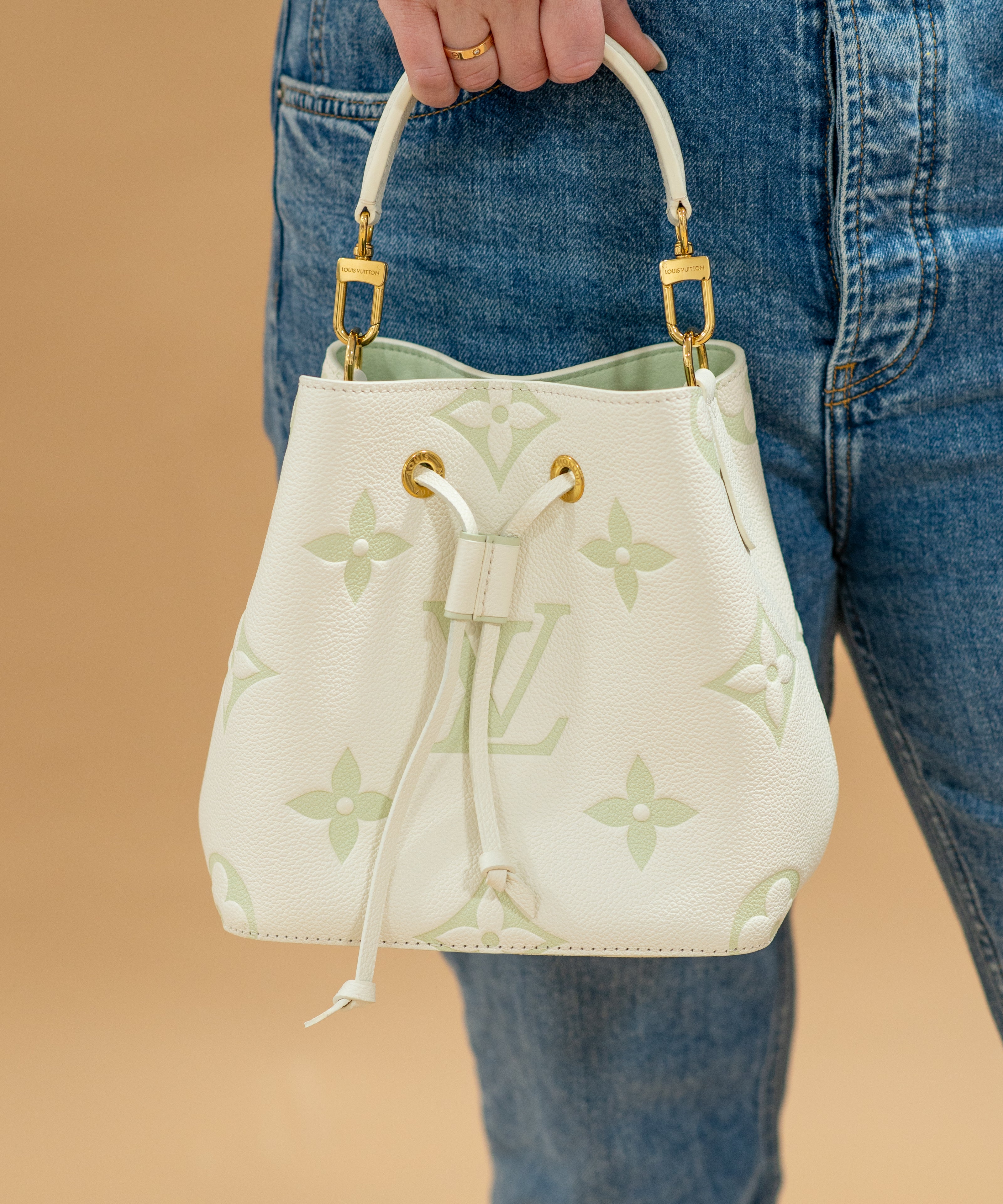 Louis Vuitton Bicolor Monogram Matcha Empriente Neo held in a hand agains jeans