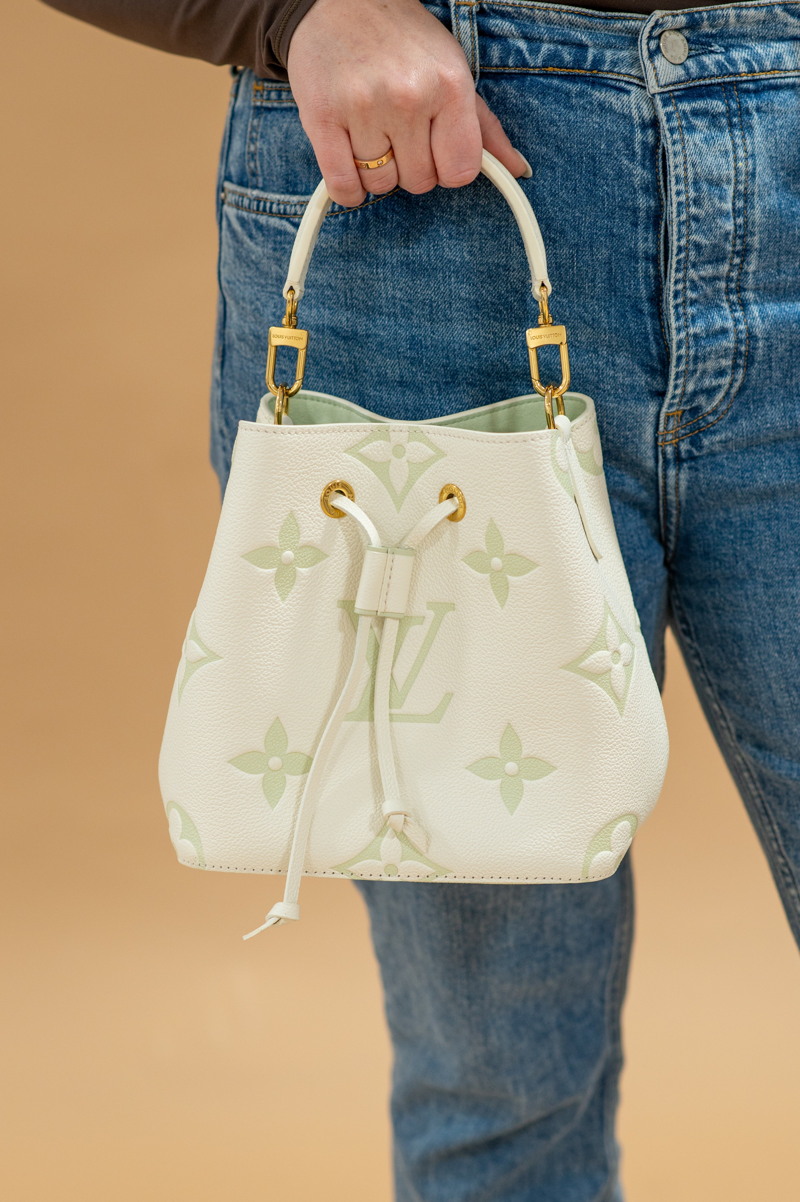 Louis Vuitton Bicolor Monogram Matcha Empriente Neo held in a hand agains jeans